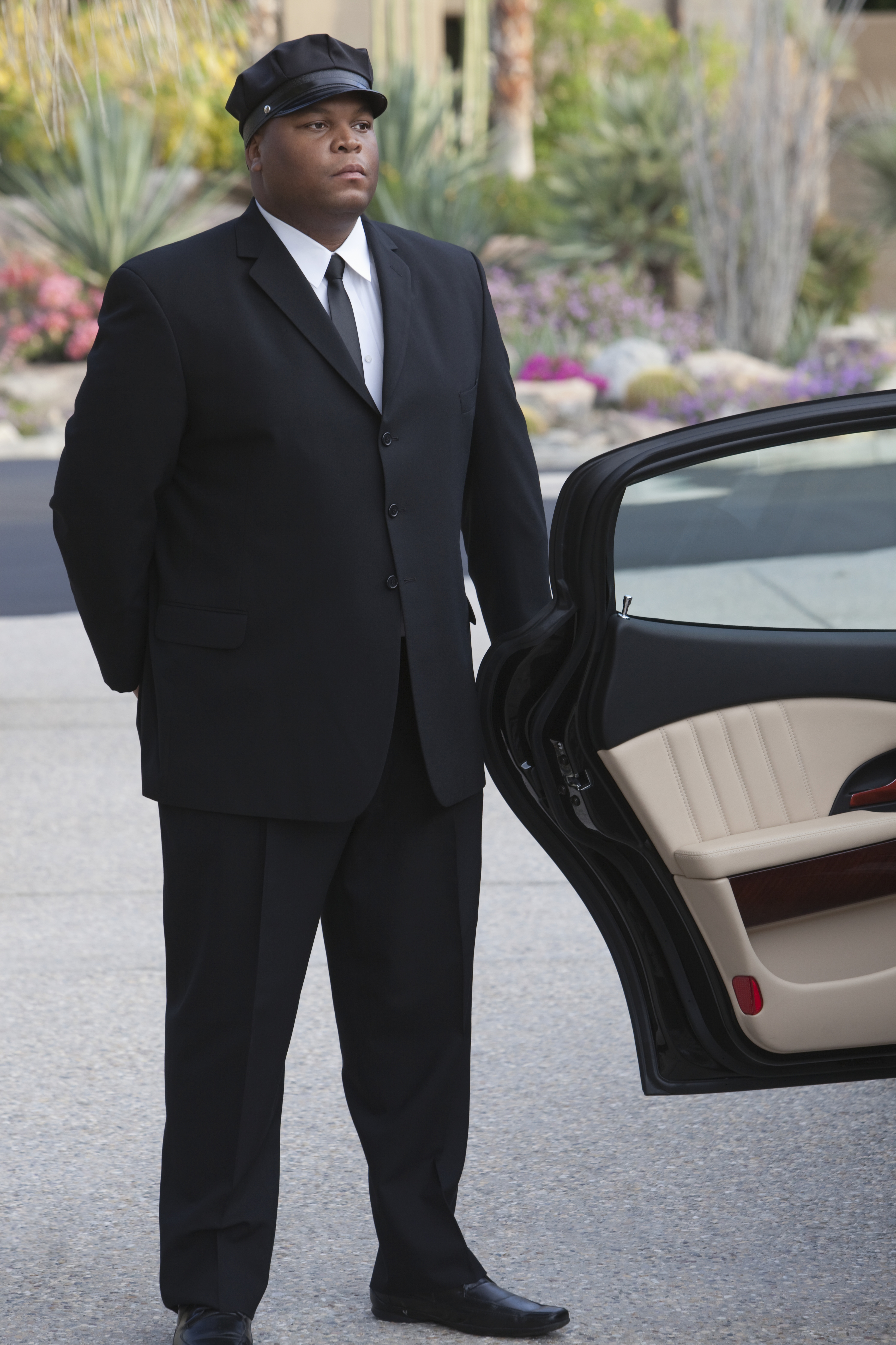 A Blacklane guest steps out of a black car with her chauffeur holding the door open.